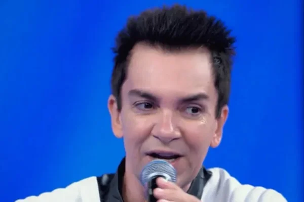 Foto colorida de um homem branco, com cabelo preto, segurando um microfone - Metrópoles