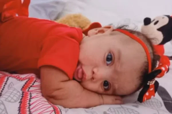 Foto colorida de bebê deitada, vestida com roupa vermelha - Metrópoles