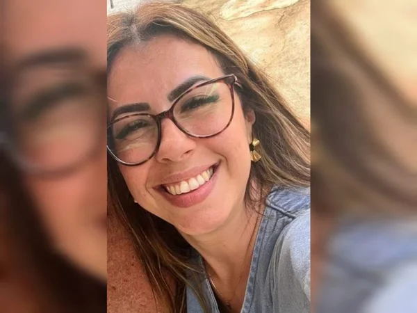 Imagem de mulher com cabelo castanho e óculos de armação preta, sorrindo - Metrópoles