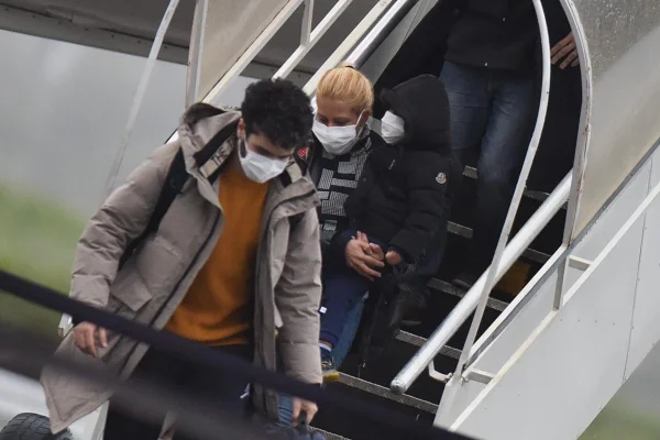 Imagem colorida mostra pessoas desembarcando de avião com máscara - Metrópoles