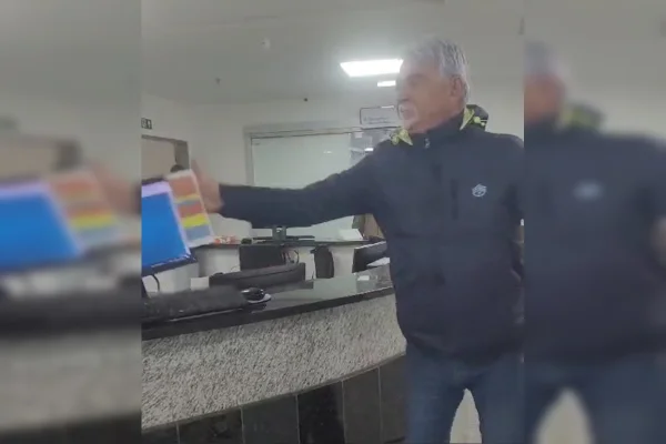 Imagem colorida de um homem, vestindo casaco e calças azuis, dando um tapa em uma tela de computador