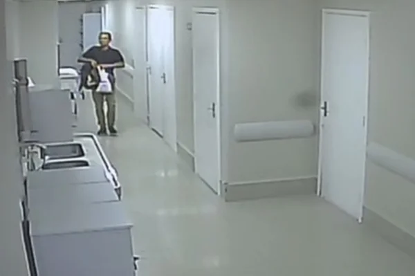 Homem andando em corredor branco de hospital - Metrópoles