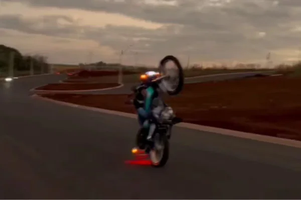 Imagem colorida mostra criança fazendo manobra de moto. Metrópoles
