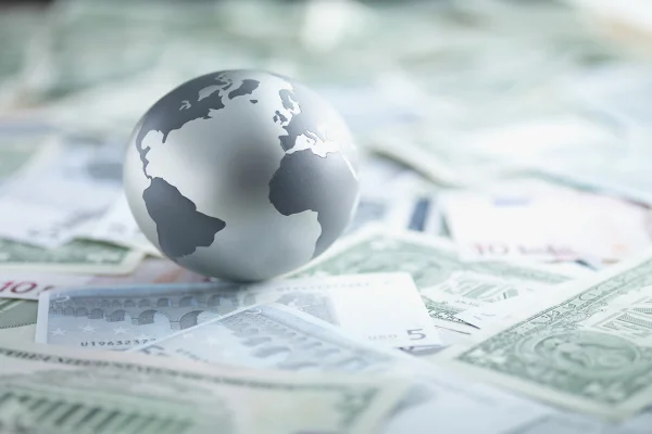 Imagem de uma miniatura do planeta Terra colocado sobre várias cédulas de dólar - Metrópoles