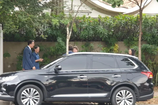 Foto colorida do ministro da Educação, Camilo Santana, de terno azul caminhando atrás de carro preto