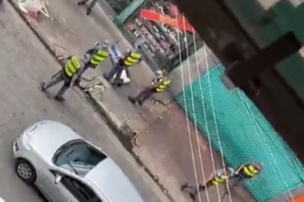 Imagem colorida de homem caído no chão rodeado por PMs. Metrópoles