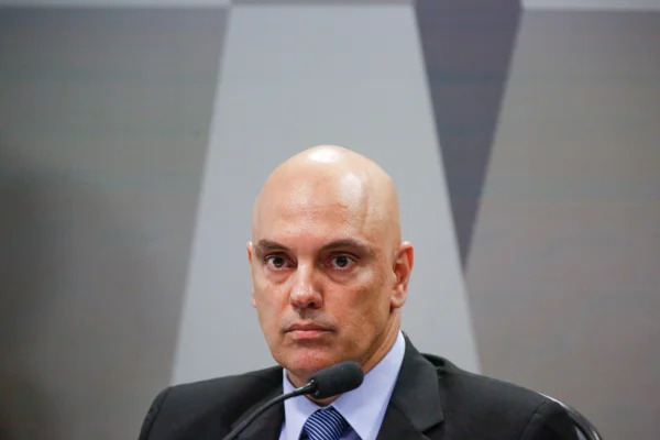 Imagem colorida de Alexandre de Moraes, sozinho à frente de fundo cinza, careca e de terno - Metrópoles