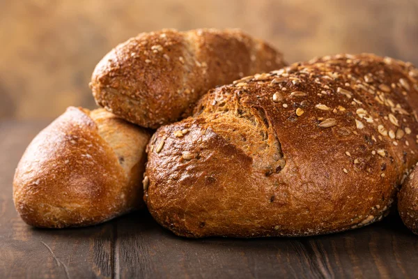 Variedade de pães assados ​​sobre uma mesa de madeira. Glúten, doença celíaca. Metrópoles