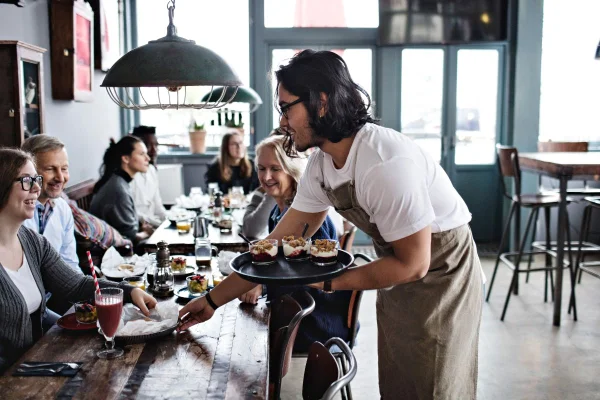 foto colorida garçom tirando os pratos da mesa em restaurante