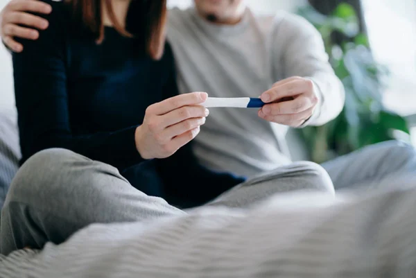 Imagem de casal segurando teste de gravidez - Metrópoles