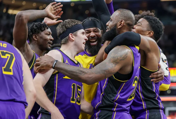 Imagem colorida de LeBron James sendo abraçado por colegas - Metrópoles