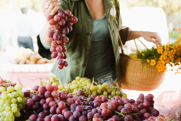 Foto colorida de mulher segurando cacho de uvas - Metrópoles