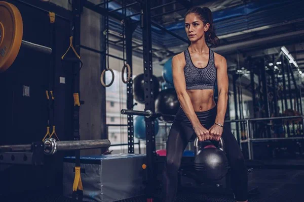 Jovem mulher faz exercício usando kettlebell