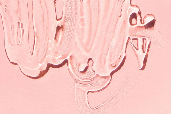 Lubrificante transparente espalhado em fundo cor de rosa - Metrópoles