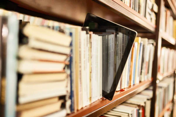 Livro e-book no meio de estante com vários livros, puxado para o lado