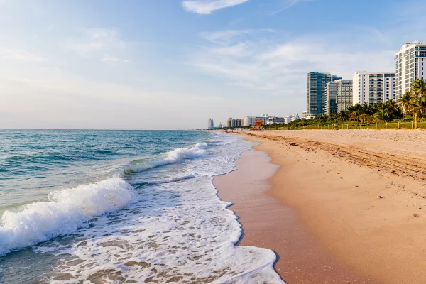 Foto colorida de praia, areia e prédios - Metrópoles.