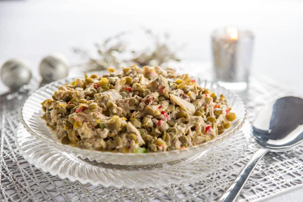 Na foto, um prato grande transparente com salada de lentilha com pernil