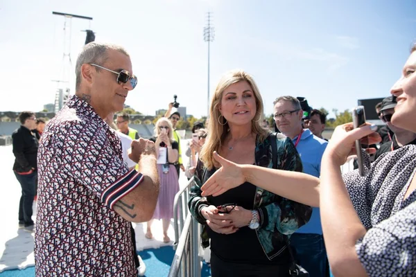 Robbie Williamns negando aperto de mão e oferecendo cotovelo para ser tocado por fã em virtude da pandemia de coronavírus