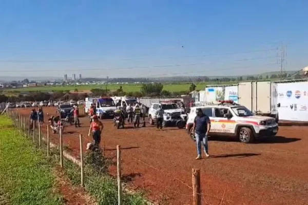 Imagem de viaturas da Polícia Militar e pessoas em estrada de terra, próximo a tendas onde houve uma acidente envolvendo helicóptero - Metrópoles