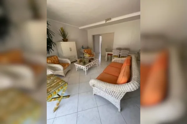 Imagem colorida de uma sala de estar pintada em branco, com sofás e cadeiras de encosto para repouso - Metrópoles