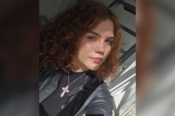 Imagem colorida mostra o rosto de Ianca Victoria de Oliveira Silva, uma mulher branca, de cabelos avermelhados ondulados, vestida de preto