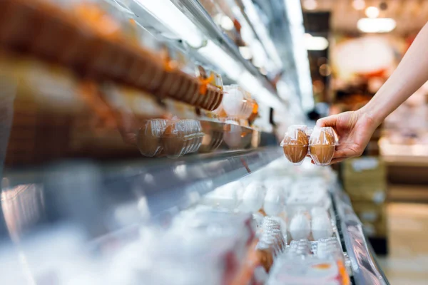 Imagem de consumidor pegando ovos em prateleira de mercado - Metrópoles