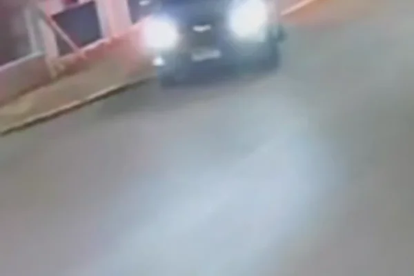 Imagem colorida de carro dirigido por adolescente pendurado em alambrado de posto de saúde. Metrópoles