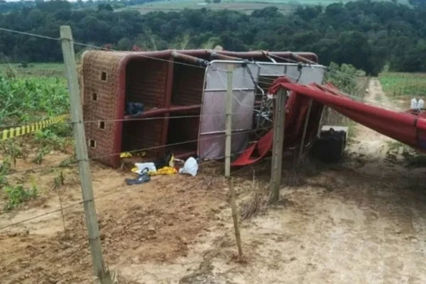 imagem colorida mostra balão caído ao lado de cerca e plantação. Acidente acabou matando mulher - Metrópoles
