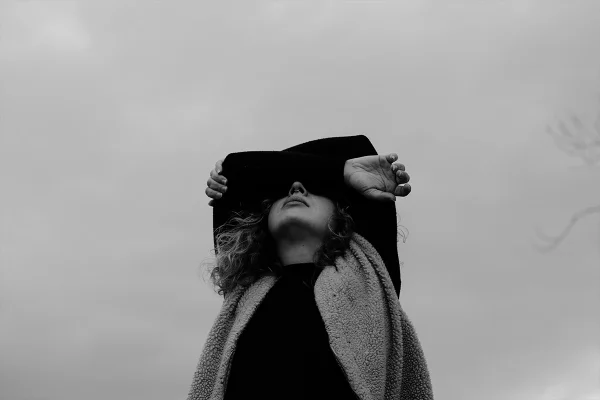 Imagem em preto e branco de mulher cobrindo os olhos com os braços - Metrópoles