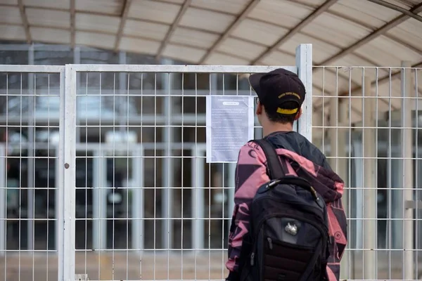 Aluno em frente a escola fechada