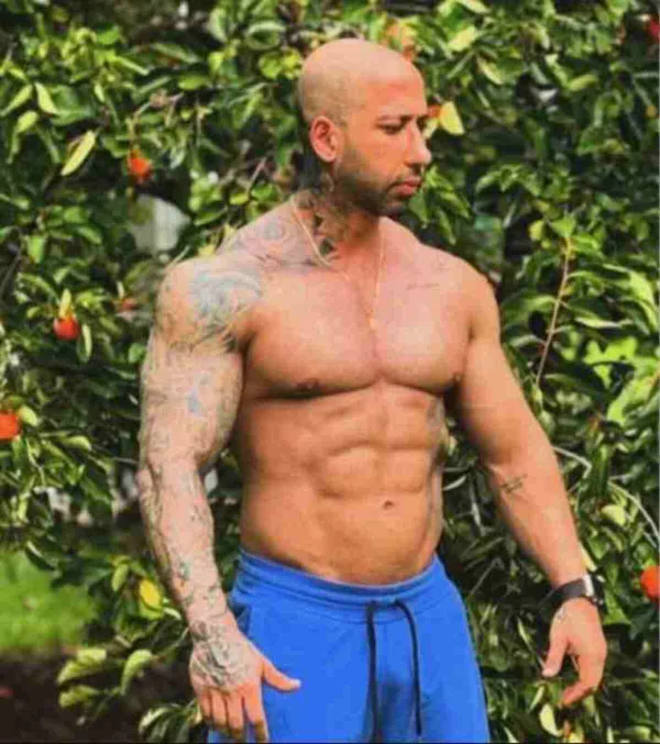 Foto colorida. Homem sem camisa com shorts azul