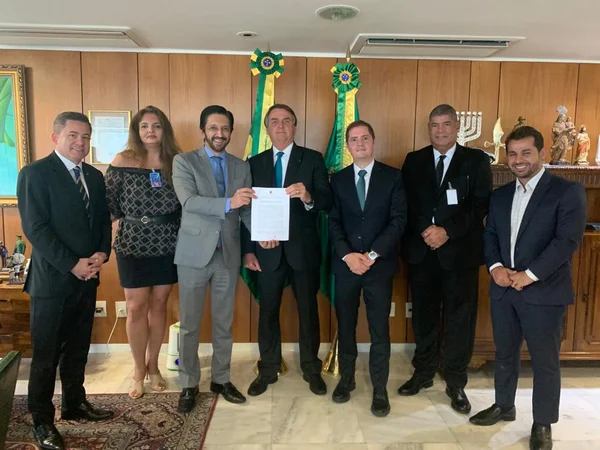 O presidente Bolsonaro posa para foto com Ricardo Nunes, prefeito de São Paulo, e outras autoridades exibindo documento de acordo sobre Campo de Marte - Metrópoles