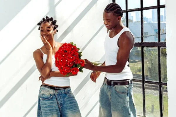 A imagem mostra um rapaz dando flores para sua namorada.