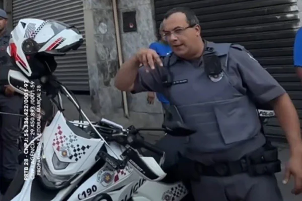 Foto colorida de policial militar fardado fazendo o gesto do M com as mãos durante agenda de campanha de Pablo Marçal na Brasilândia, zona norte de SP - Metrópoles