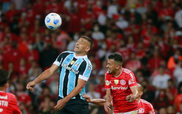Diego Souza, do Grêmio, disputa a bola com Rodrigo Lindoso, do Internacional