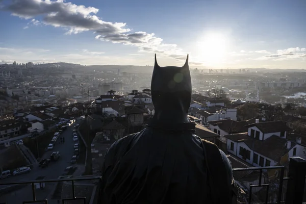 Imagem mostra homem vestido de batman olhando uma cidade de cima - Metrópoles