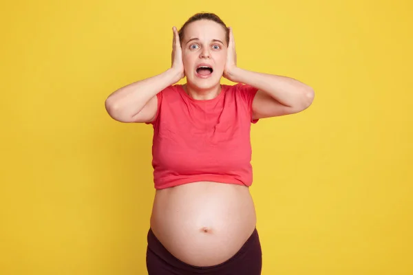 Mulher grávida tampando os ouvidos e gritando