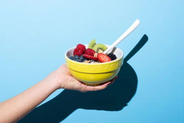 Imagem colorida de pessoa segurando pote com frutas