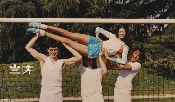 Na imagem com cor, 3 homens segurando uma mulher na frente de um gol - Metrópoles