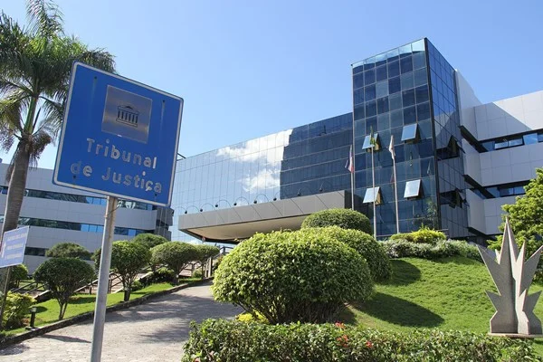 Fotografia colorida de fachada de prédio com placa escrita tribunal de justiça empresário expulso de condomínio