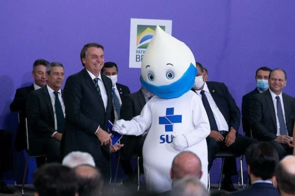 Foto colorida do presidente Jair Bolsonaro ao lado do Zé Gotinha em cerimônia do plano de vacinação no Brasil contra a Covid-19 cartão de vacina