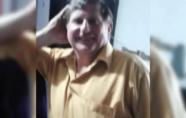 foto de um homem branco sorrindo, com uma camisa amarela