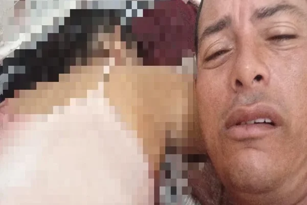 Imagem colorida homem ao lado de mulher morta - Metrópoles