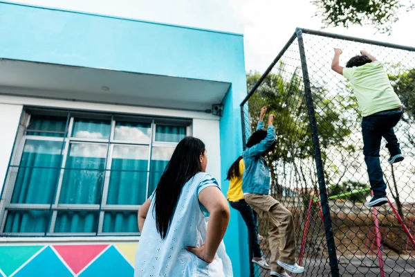 Professora repreende alunos subindo em cerca de arame no pátio da escola. Transtorno opositivo desafiador (TOD)