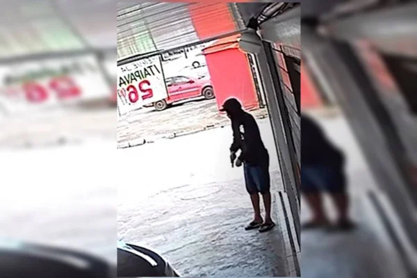 Foto colorida de homem segurando revolver em garagem