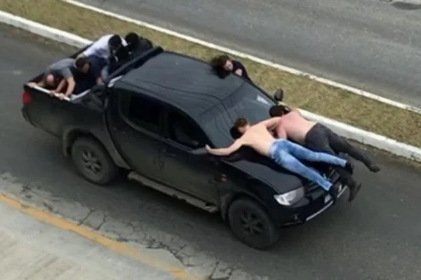 Ladrões fogem da polícia com reféns no capô de caminhonete. Veja