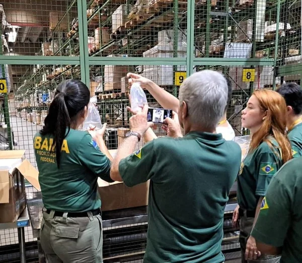 Imagem colorida de agentes do Ibama, duas mulheres e um homem, olham para embalagens plásticas - Metrópoles
