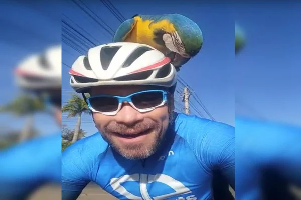 Ciclista sorri com arara em sua cabeça