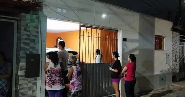 Foto colorida de pessoas paradas em frente a uma casa - Metrópoles