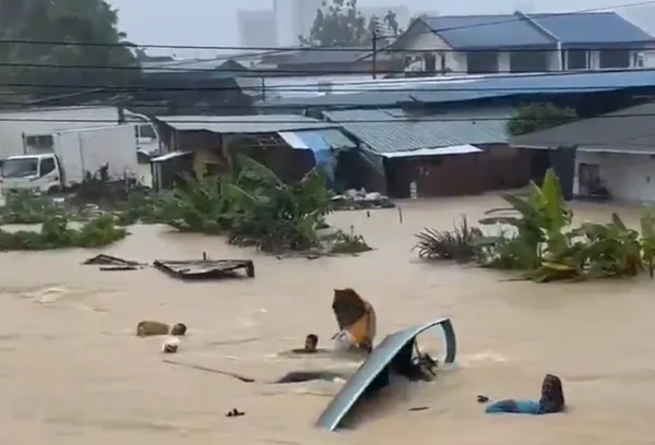 Pessoas arrastadas pela chuva na Malásia, em novembro de 2025.